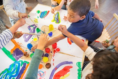 Flera barn målar vid ett stort papper med flaskfärg